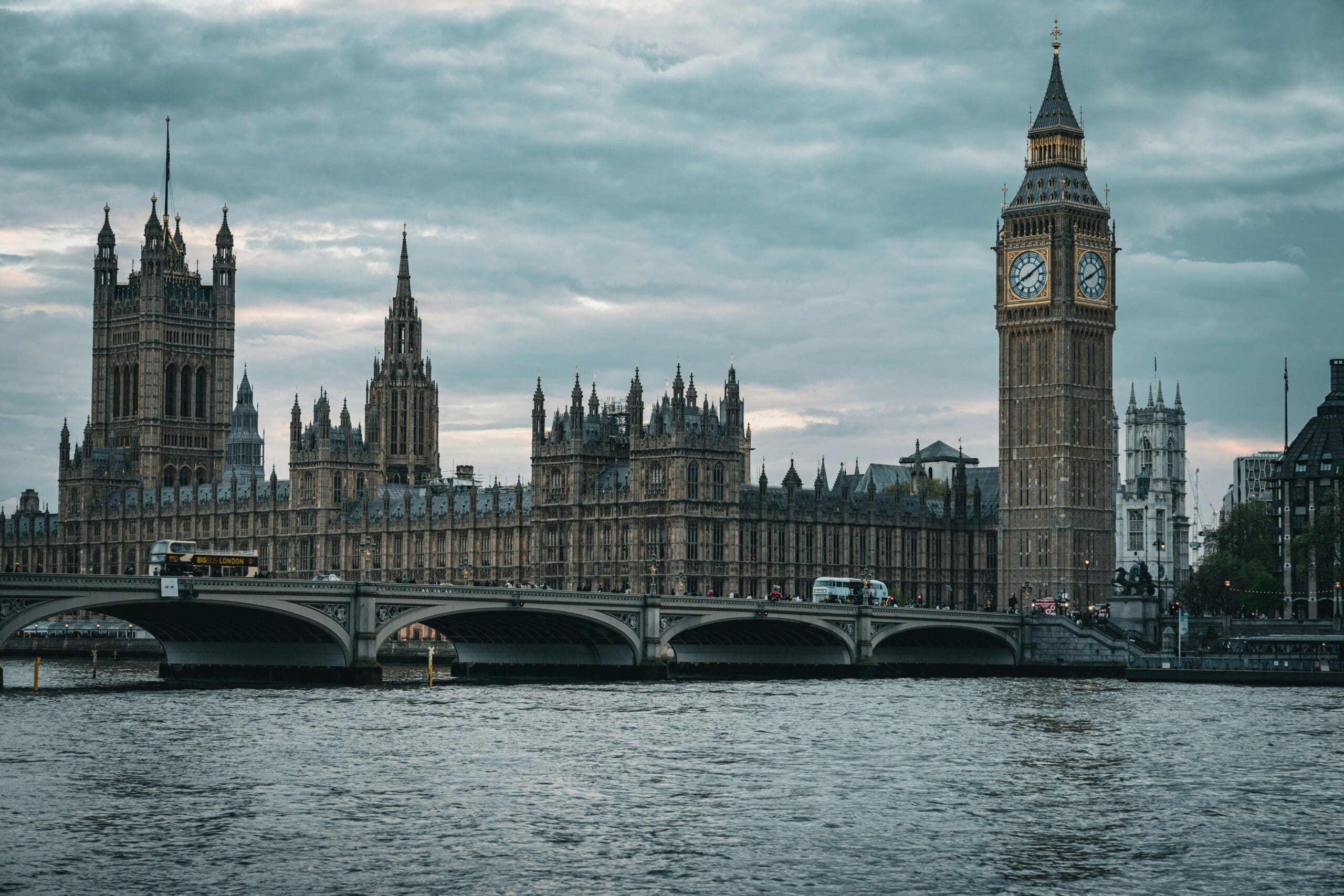 Big Ben and the Houses of Parliament in Westminster, London, against a cloudy sky, evoking parliamentary policy debate