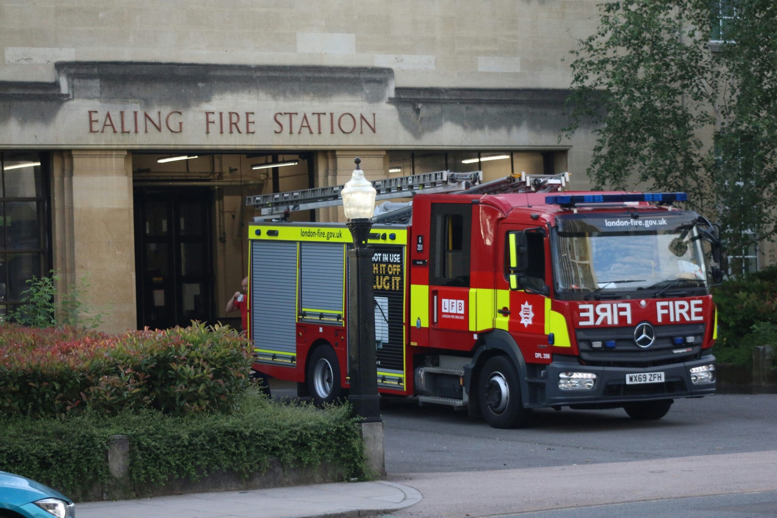 A red fire engine inside a UK fire station bay being prepared for duty