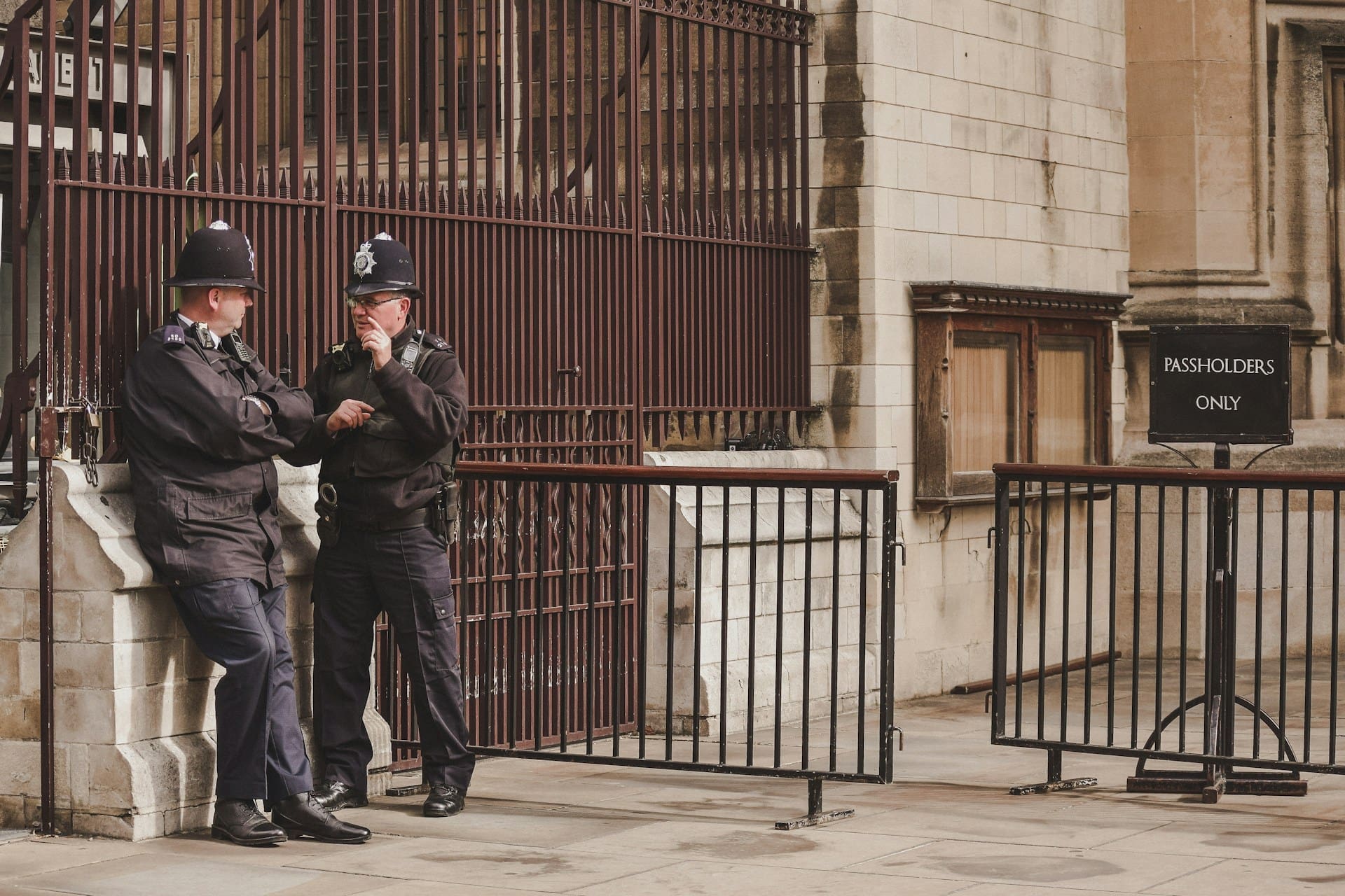 Two UK police officers in standard uniform talking on a city street